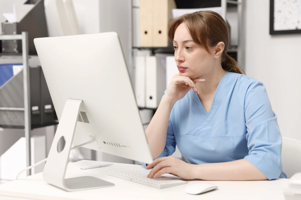 A woman is sitting at a table using a laptop computer.