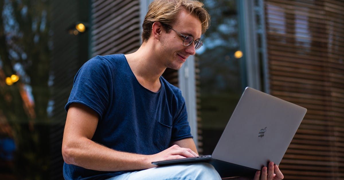 A man is sitting on the steps of a building using a laptop computer.