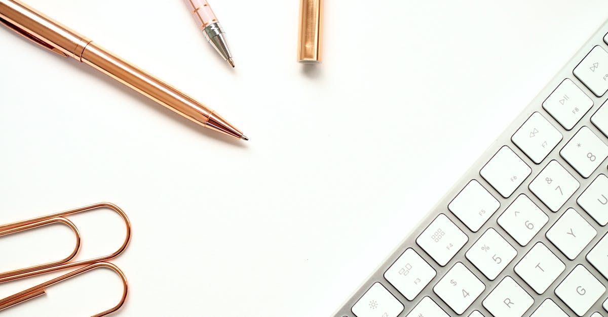 A keyboard , pencils , paper clips and scissors on a white table.