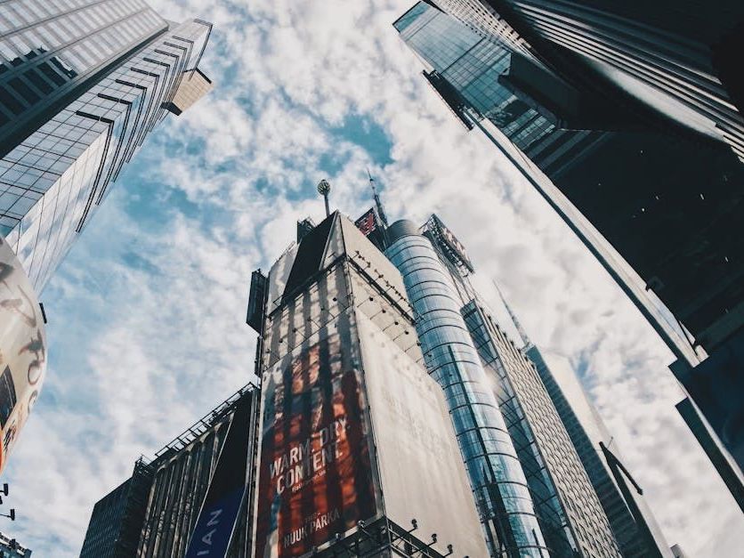 Looking up at a city skyline with a sign that says ' time square ' on it