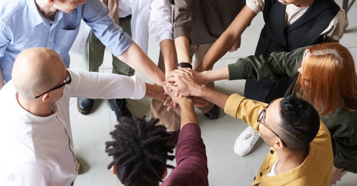 A group of people are putting their hands together in a circle.