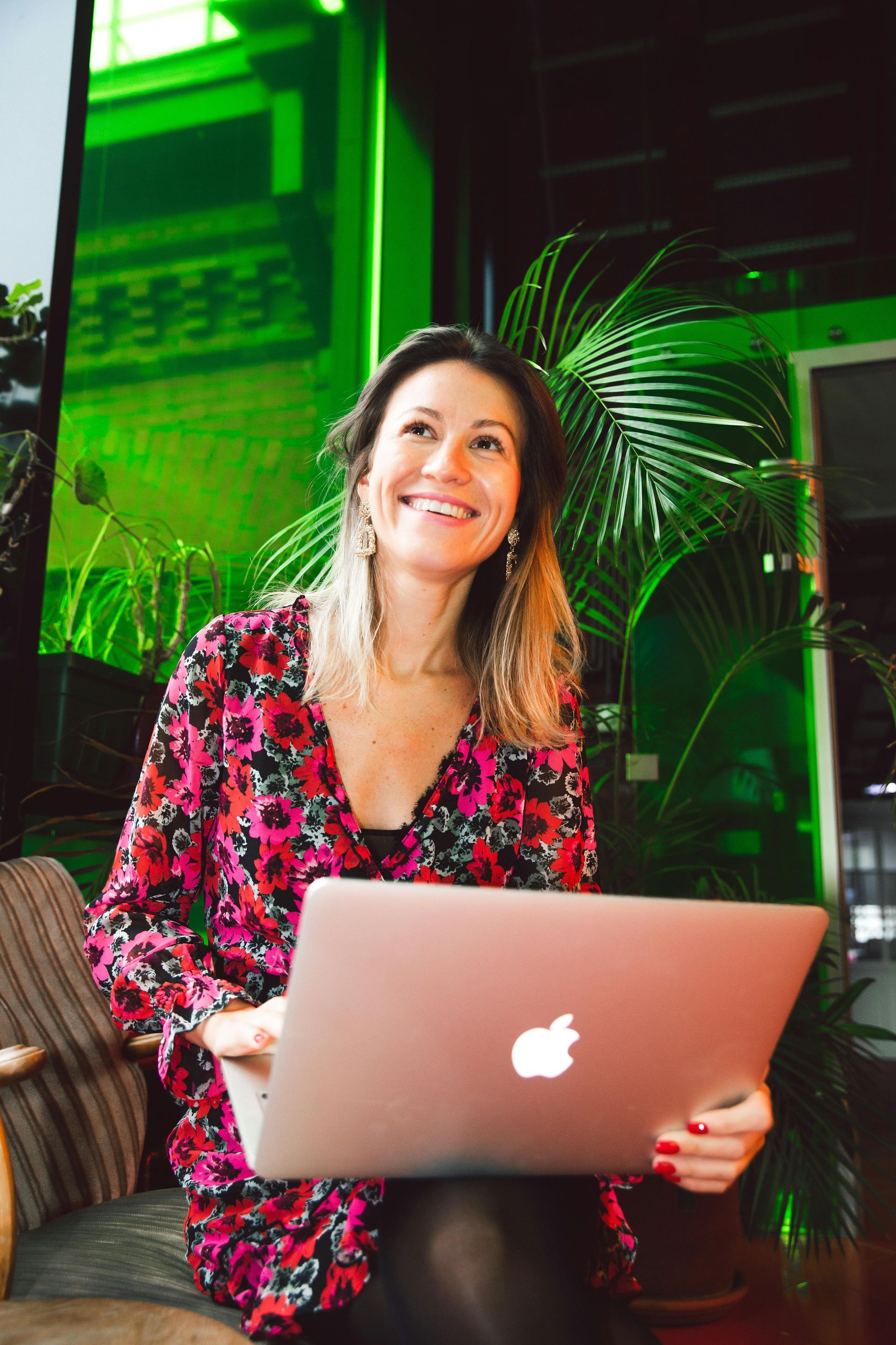 A woman is sitting in a chair holding a laptop computer.