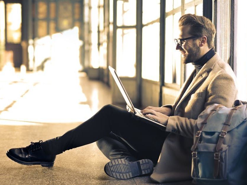 A man is sitting on the floor using a laptop computer.