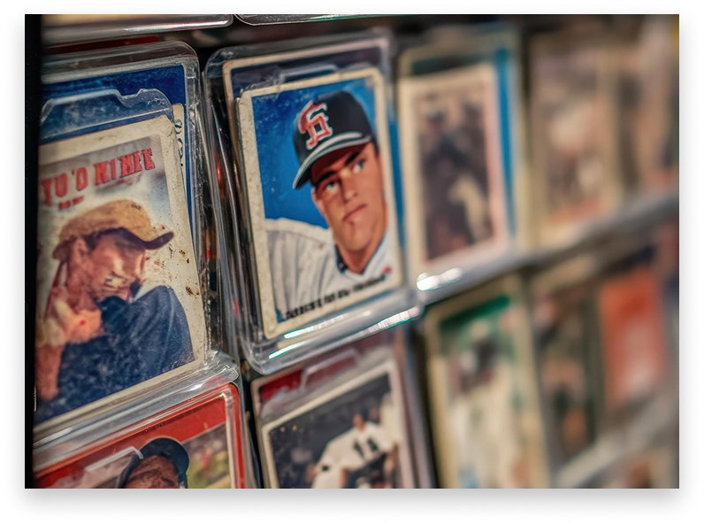 Close-up of vintage baseball cards in plastic cases, stacked on a shelf, with player portraits.