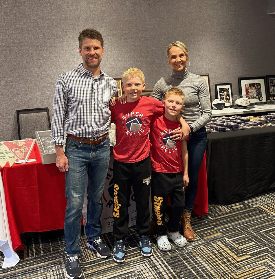 Family of four smiling, posed near a table. 