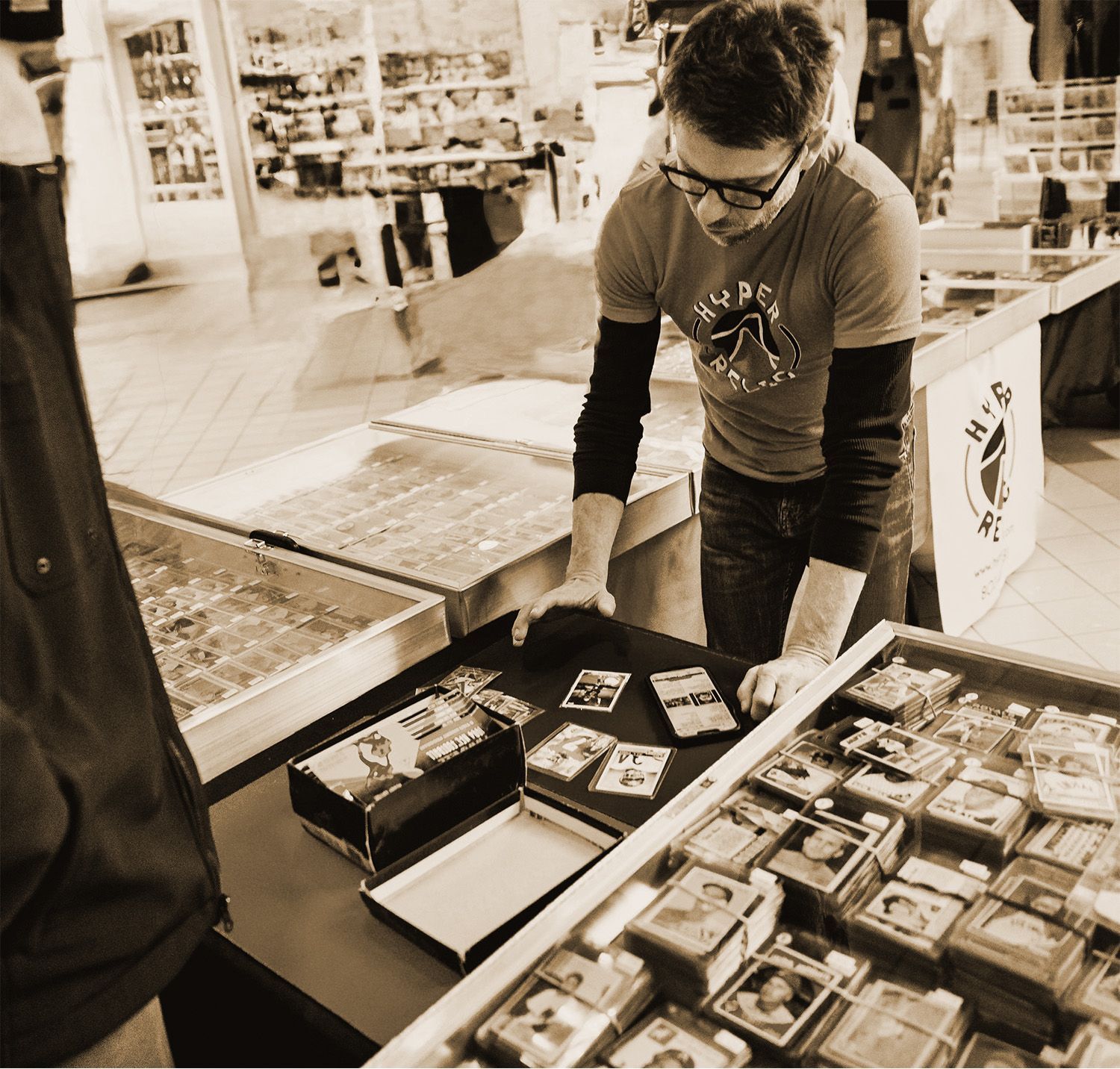 Person at a display table, sorting through trading cards. Store setting.