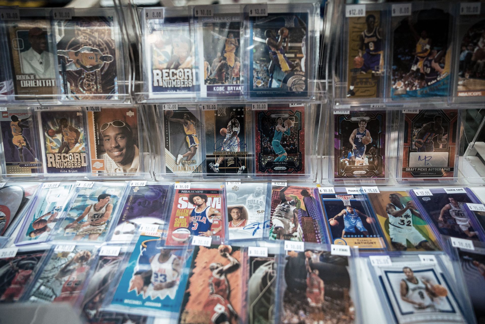 Basketball trading cards displayed in protective cases, showcasing various players at a shop or show.