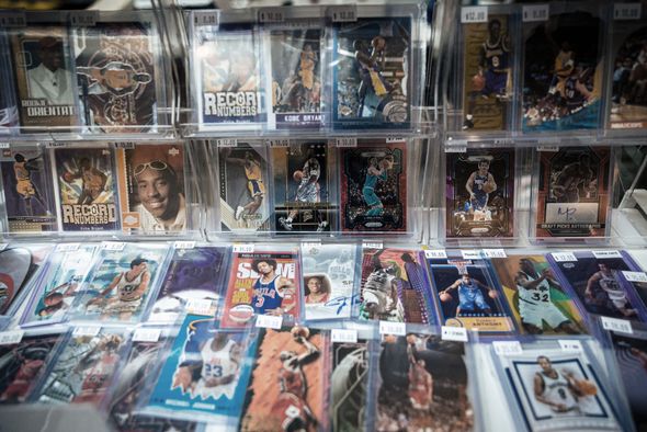 Basketball trading cards displayed in protective cases, showcasing various players at a shop or show.