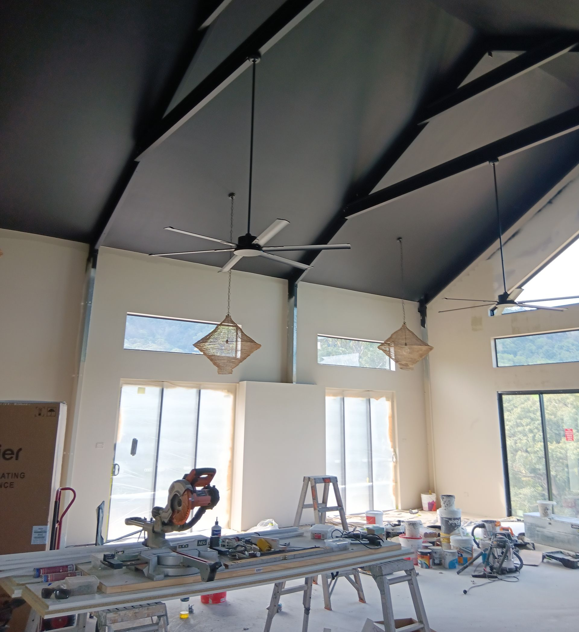 Interior view of room under construction with high, angled, black ceiling. Beige walls, open windows, and tools on a workbench — AMAC Painting & Maintenance Nowra In Nowra, NSW