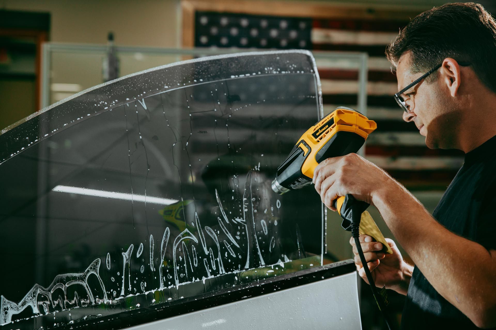 A man is wrapping a car with plastic wrap.