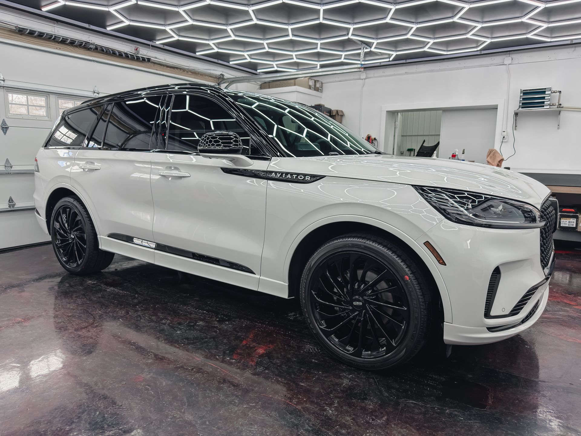 A red car is parked in a garage next to a garage door.