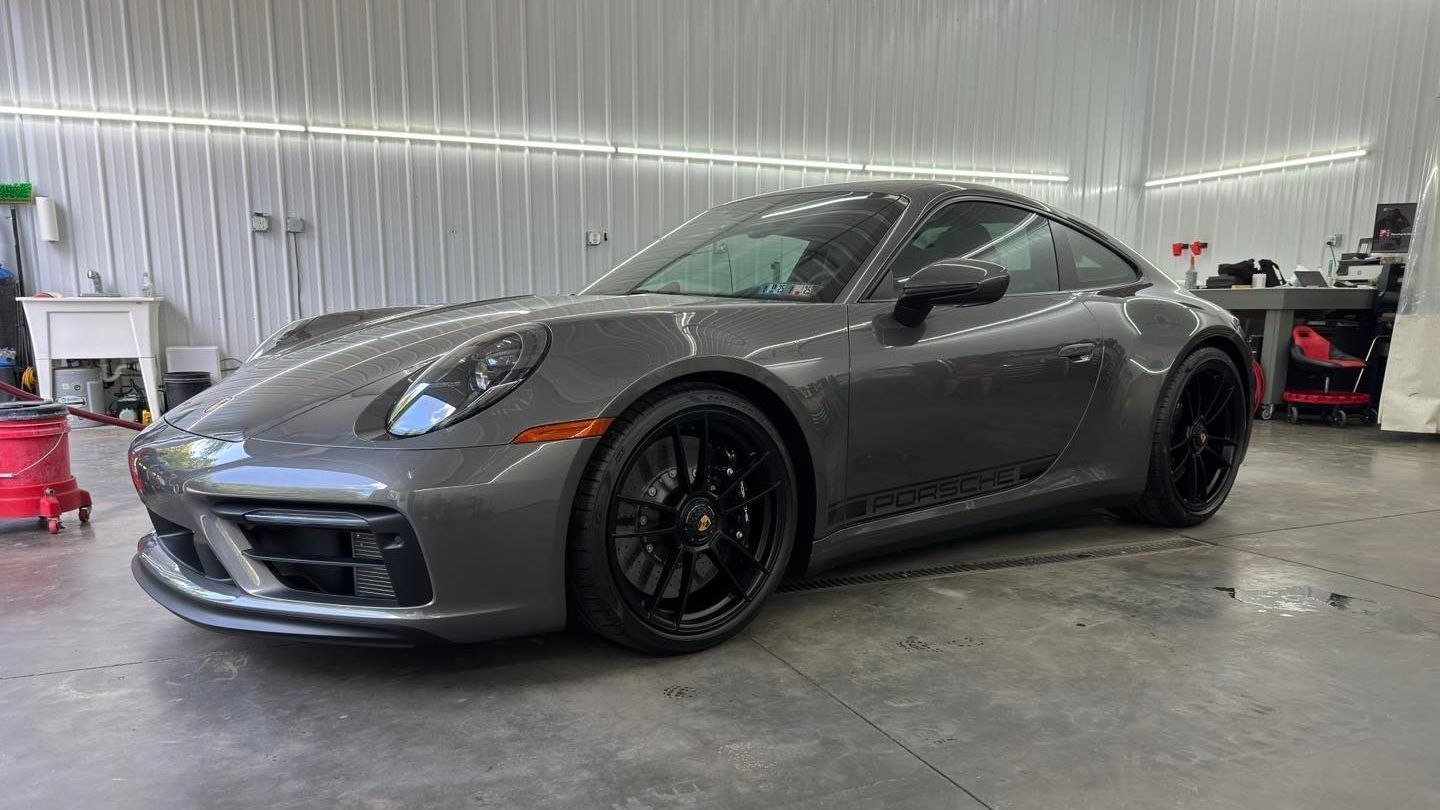 A gray porsche 911 gt3 is parked in a garage.