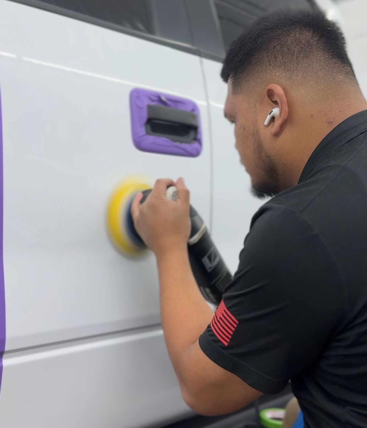 A man in a black shirt is polishing a white van