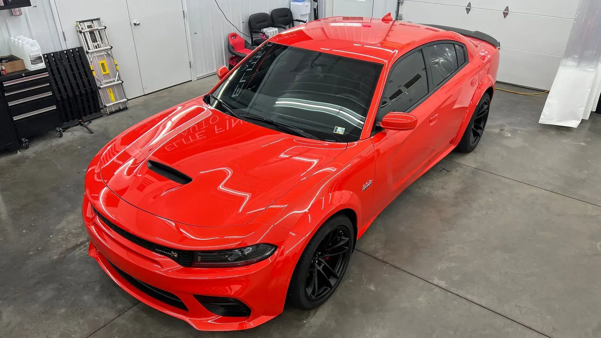 A red dodge charger is parked in a garage.