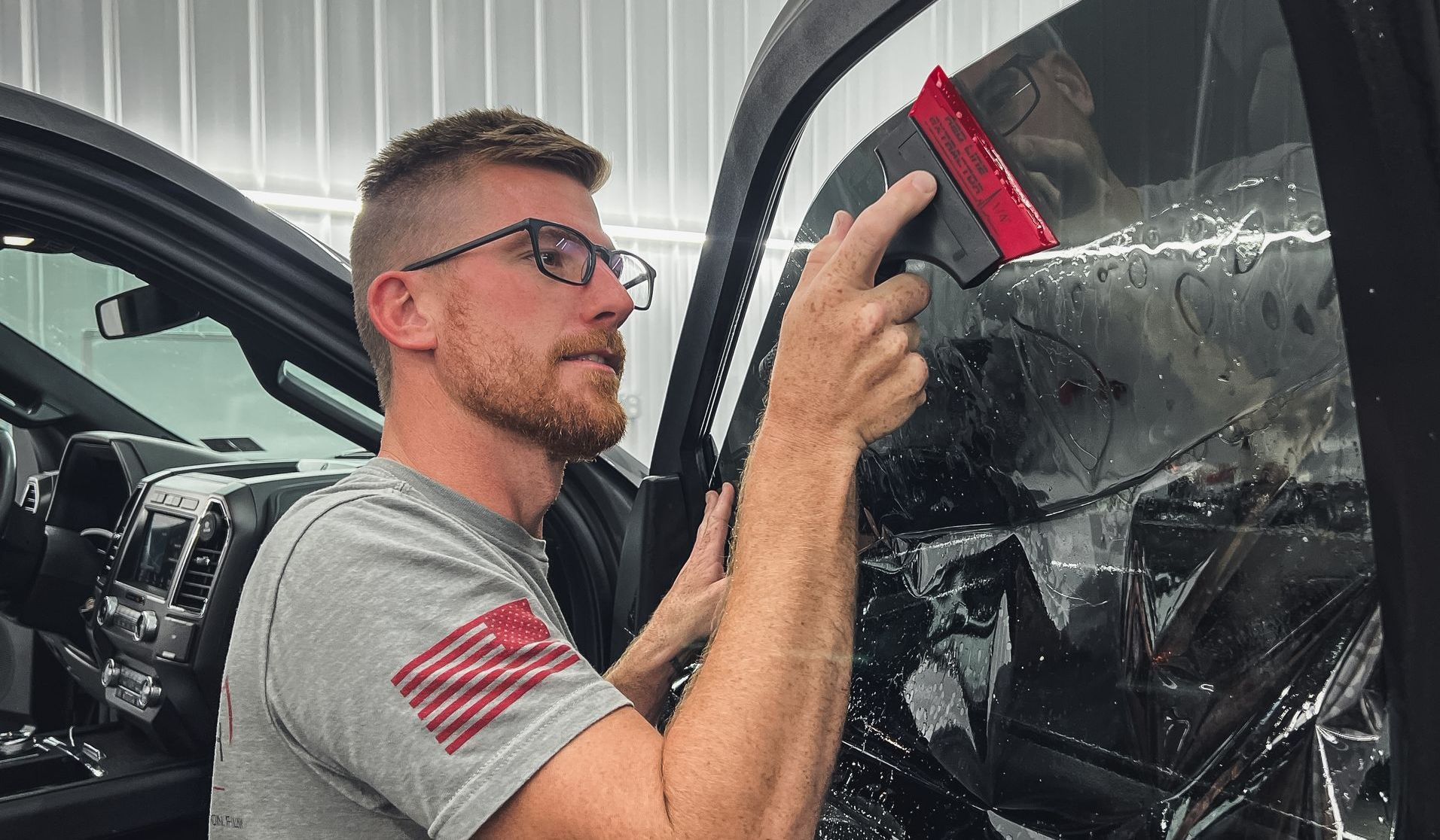 A man is polishing a black suv in a garage.