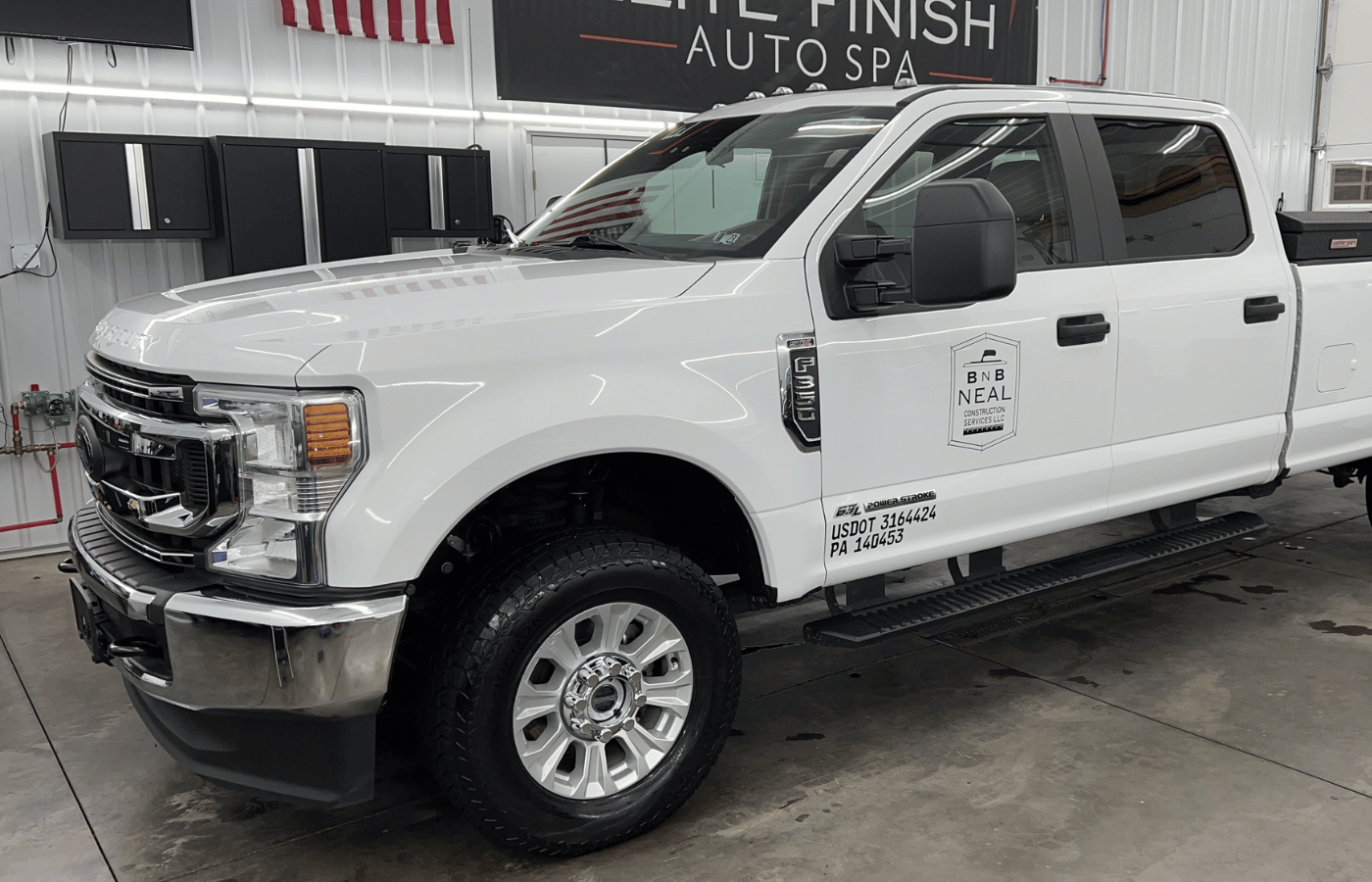 A man is polishing a black suv in a garage.
