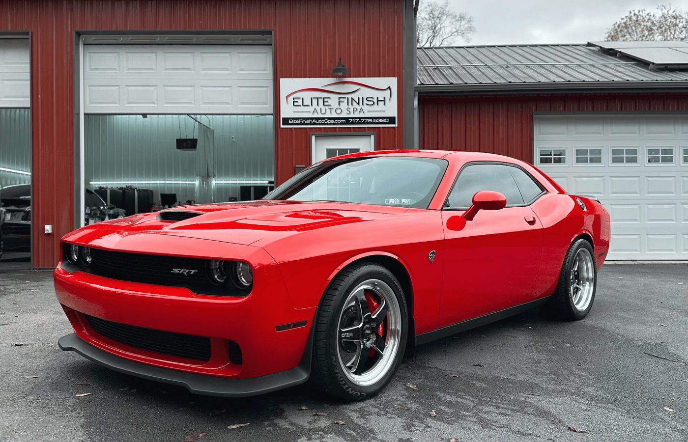 A man is cleaning the back of a white sports car.