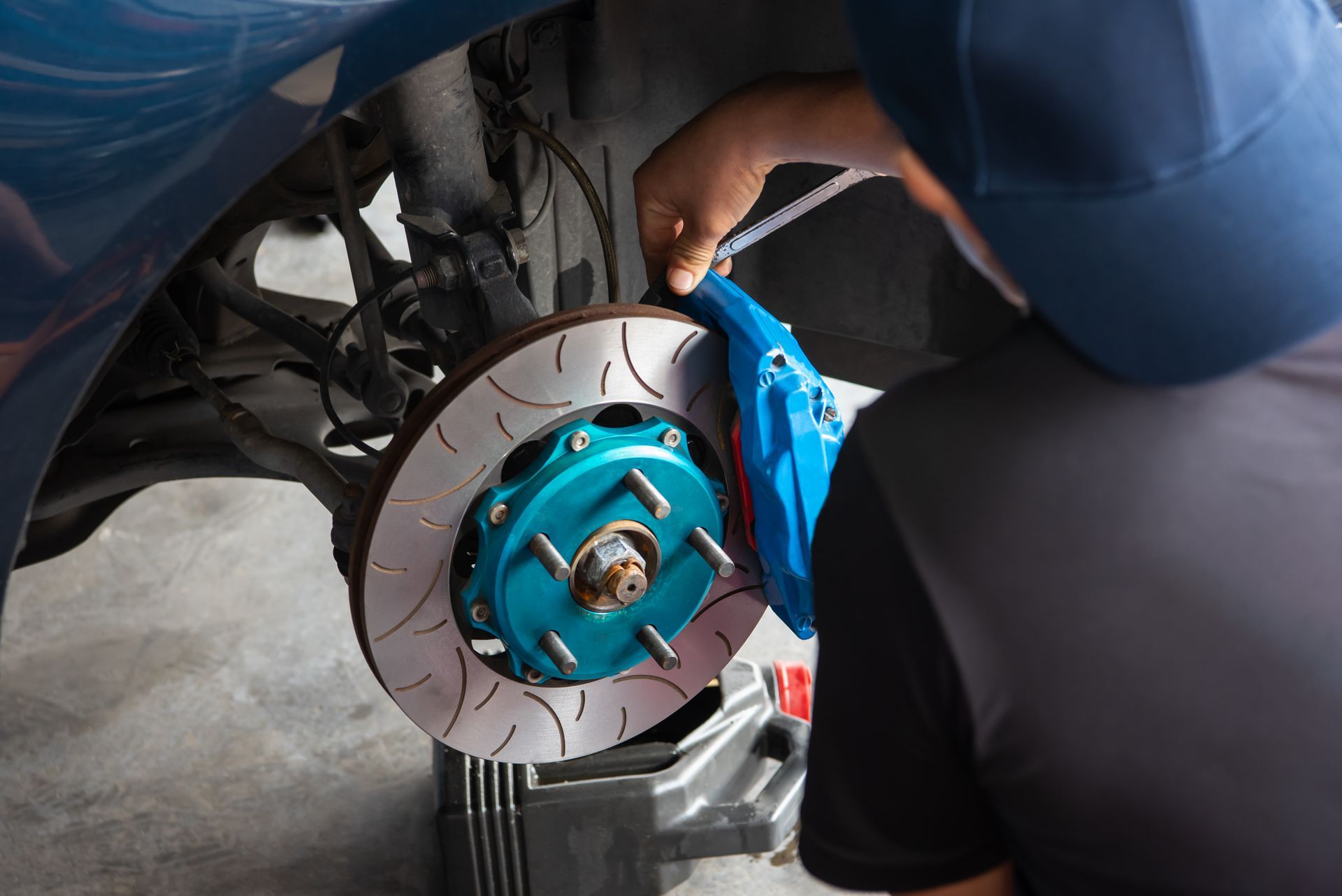 A man is working on the brake disc of a car.