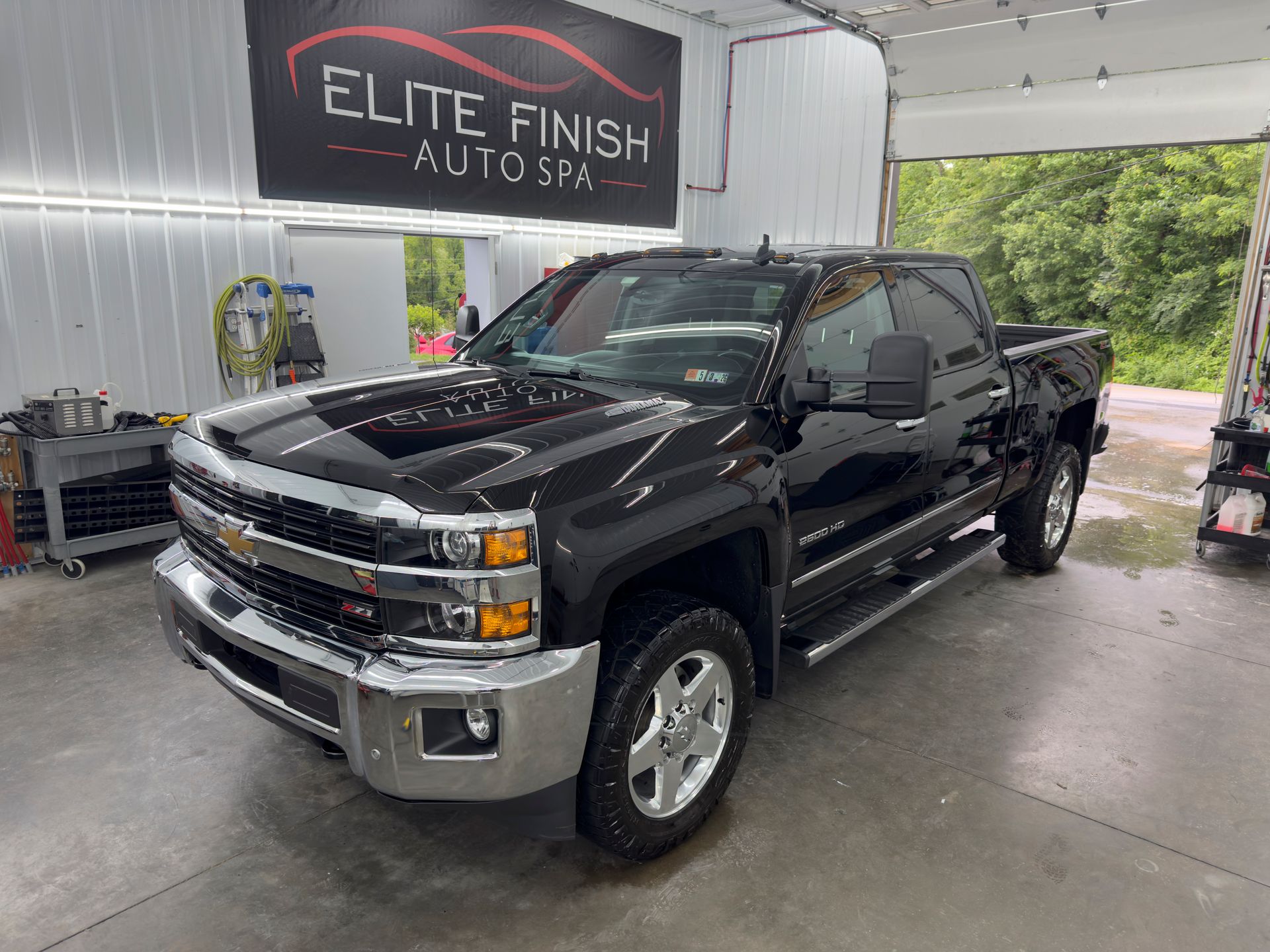 A black truck is parked in a garage next to a sign that says elite finish auto spa.