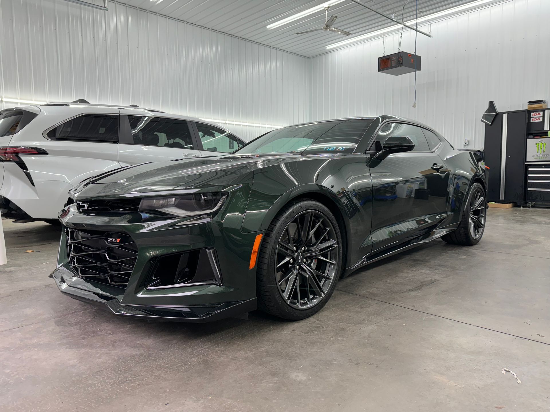 A green chevrolet camaro zl1 is parked in a garage.
