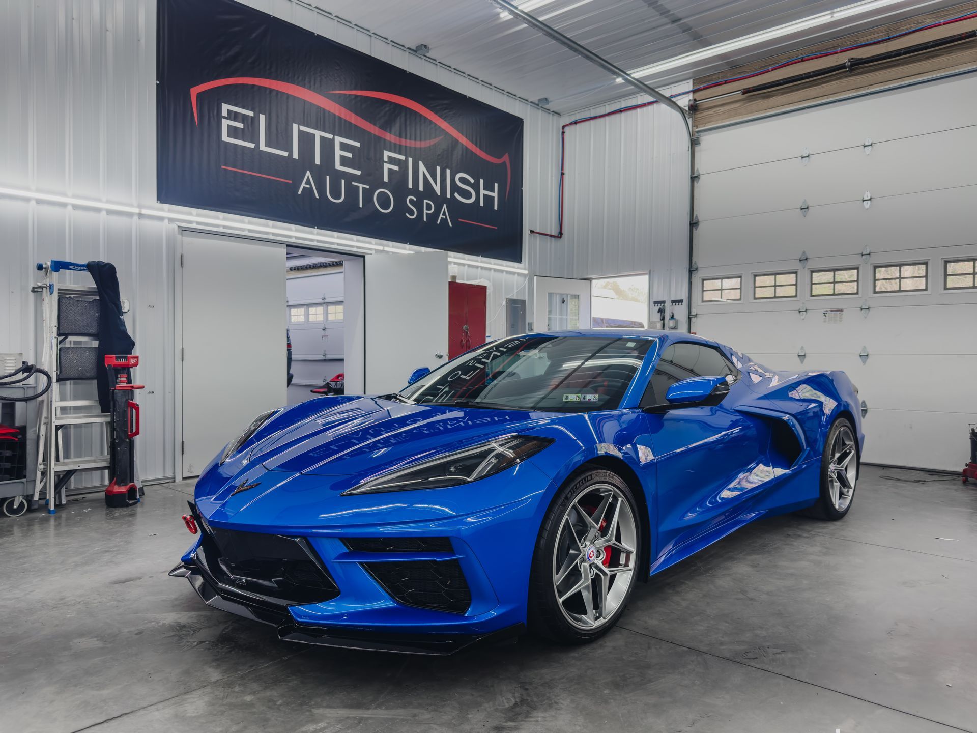 A blue sports car is parked in a garage next to a sign that says elite finish auto spa.
