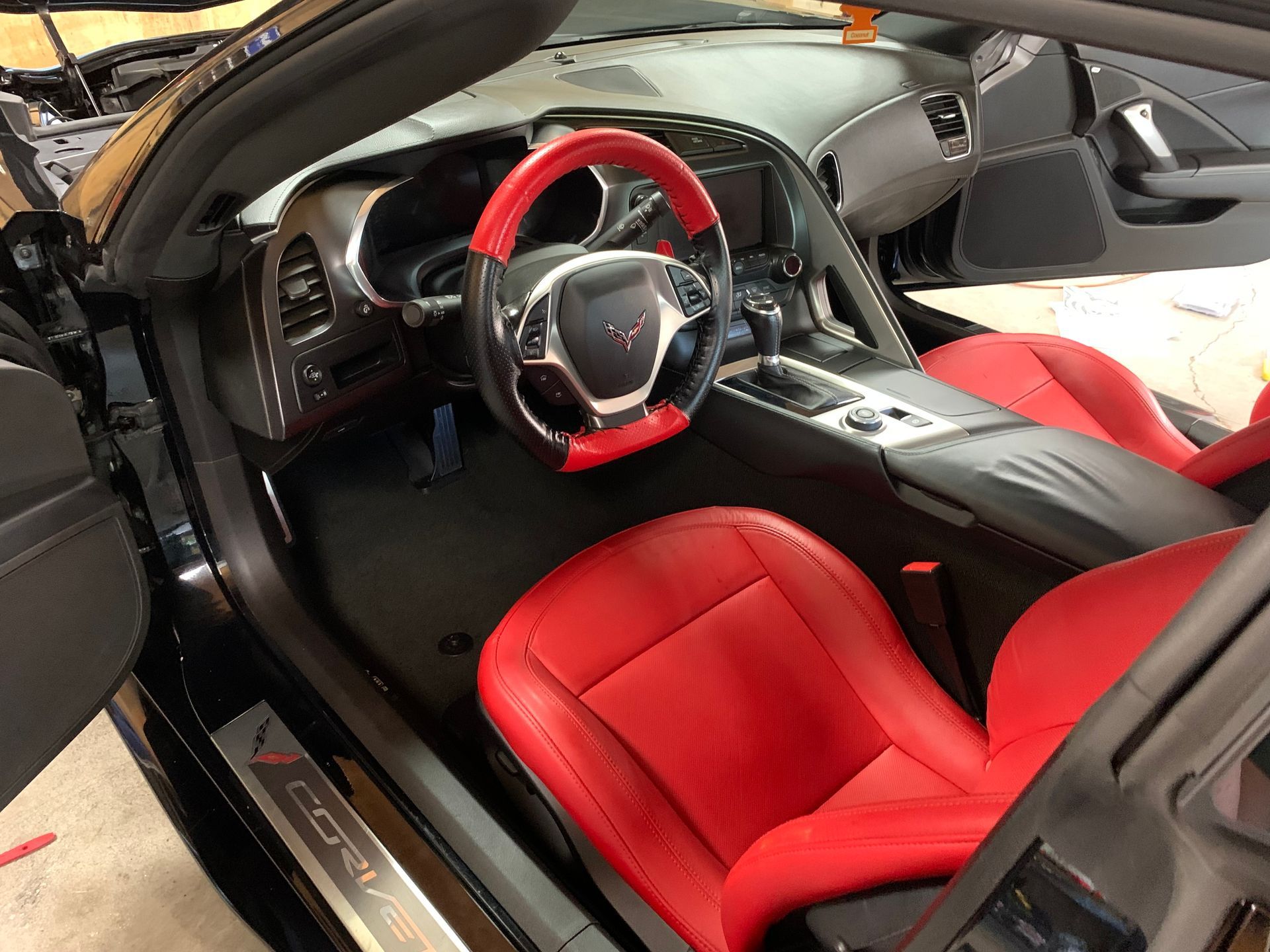 The interior of a black corvette with red seats and a red steering wheel