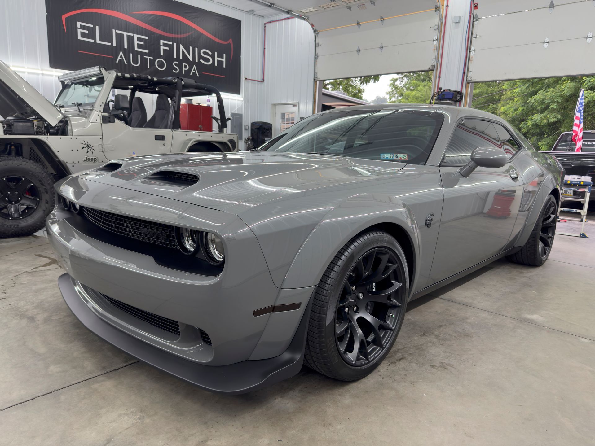 A gray dodge challenger is parked in a garage.