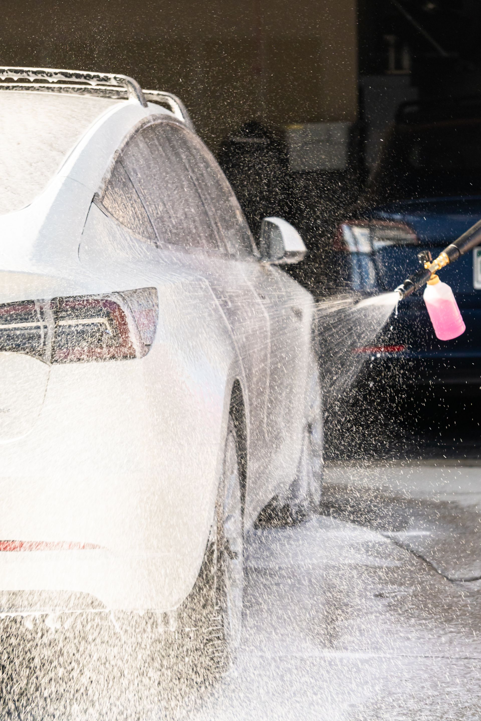 A person is washing a car with foam in a garage.