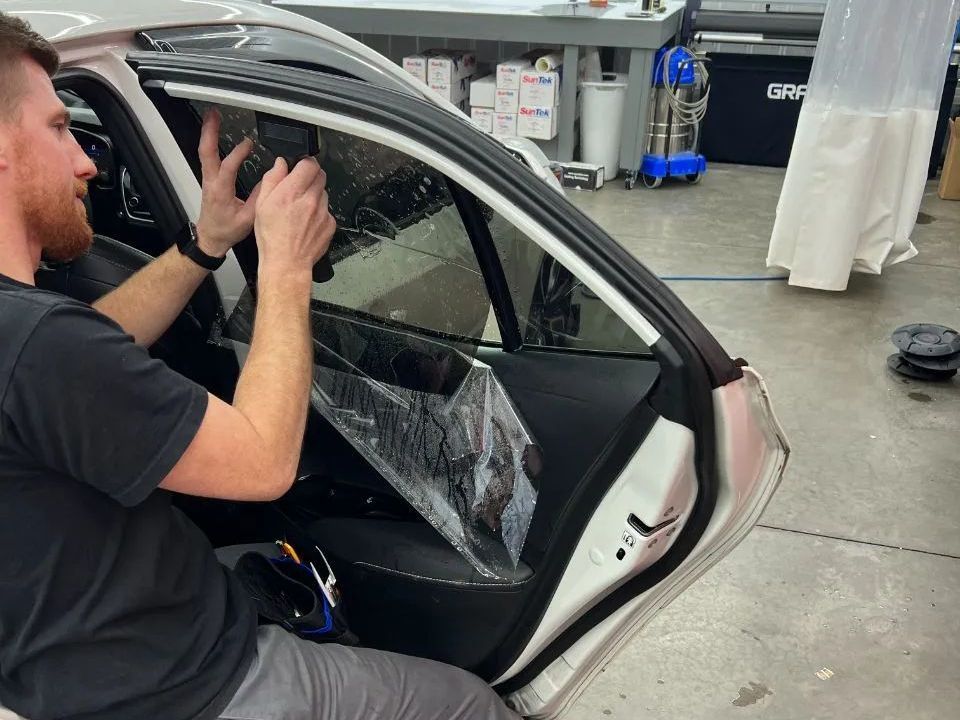 A man is wrapping a car with plastic wrap.