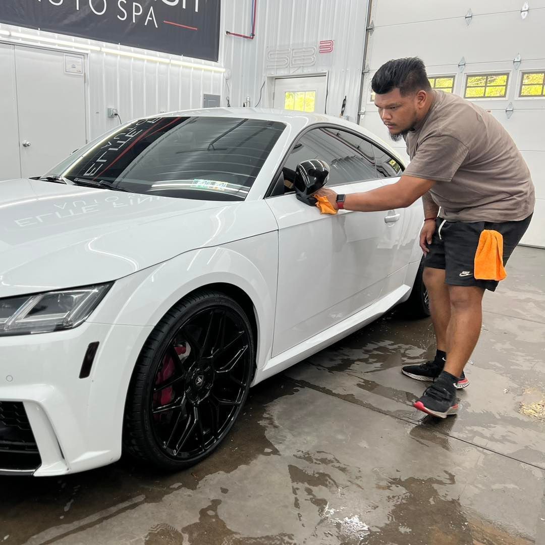 A man is wrapping a car with plastic wrap.