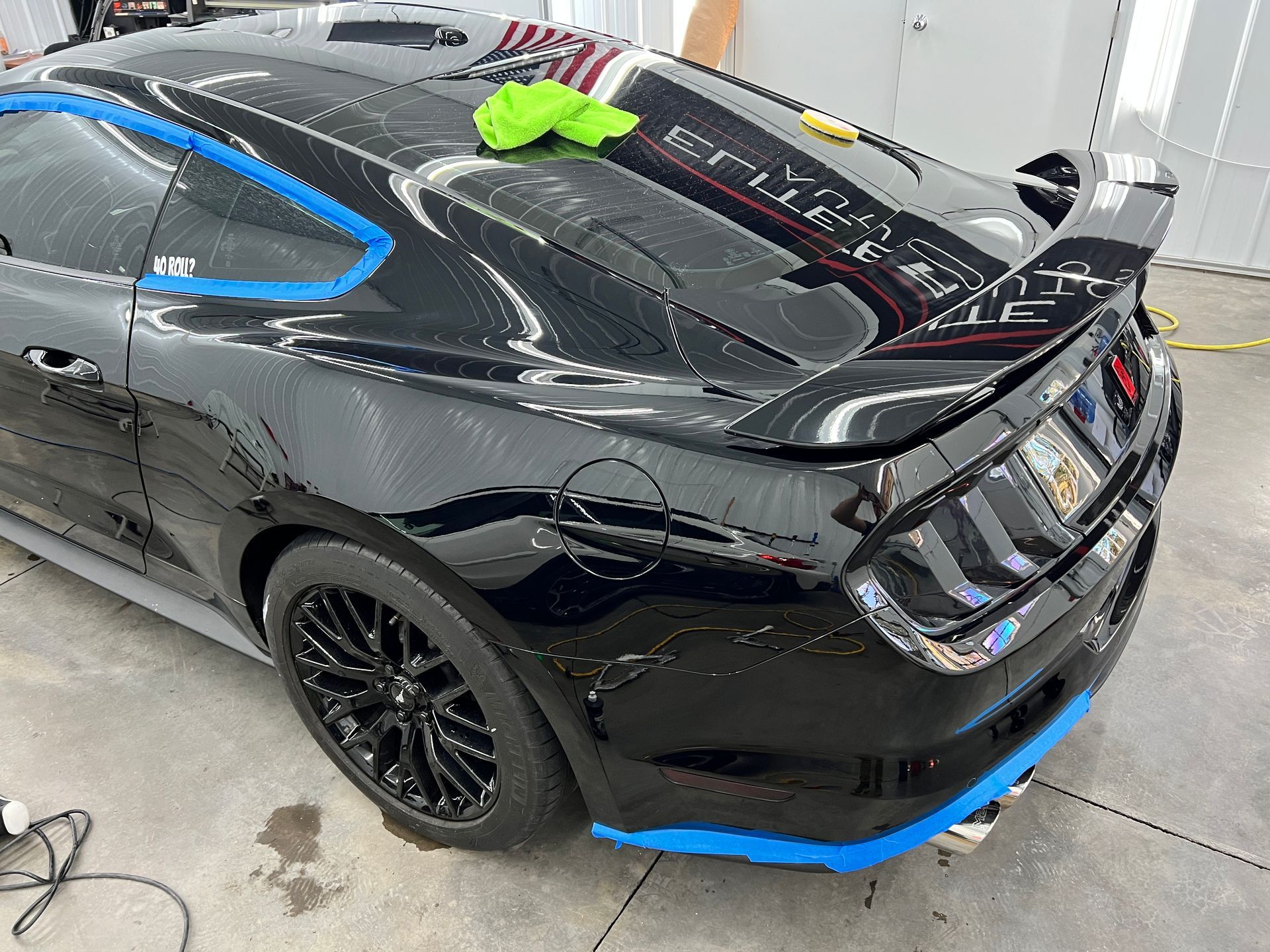 A black mustang is sitting on the ground in a garage.