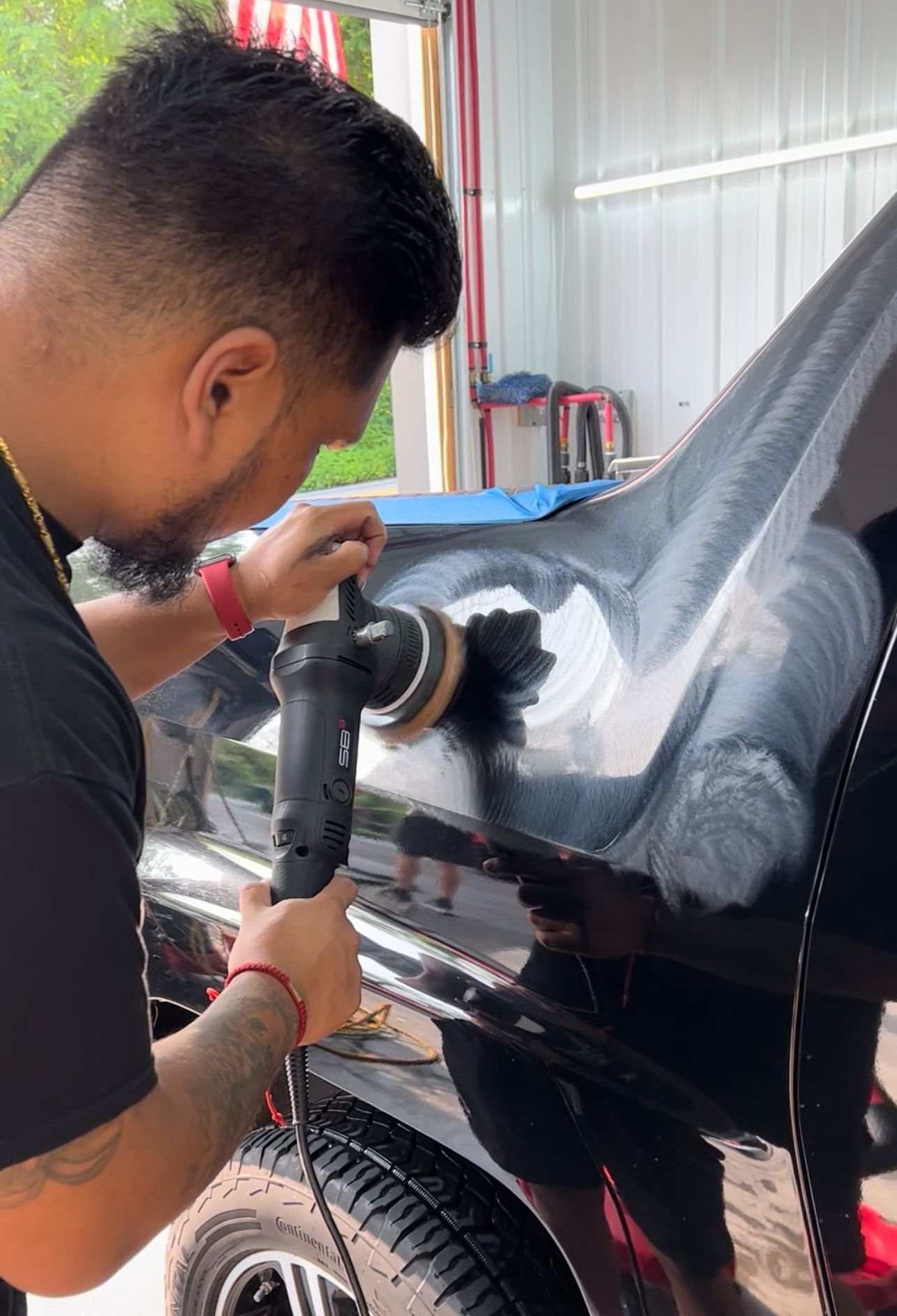 A man is polishing a black car with a machine.
