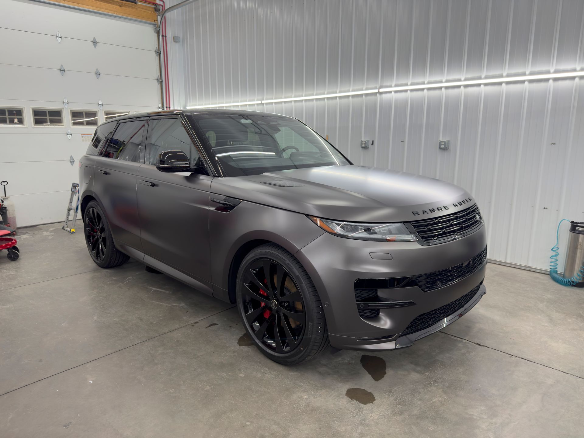 A gray range rover sport is parked in a garage.