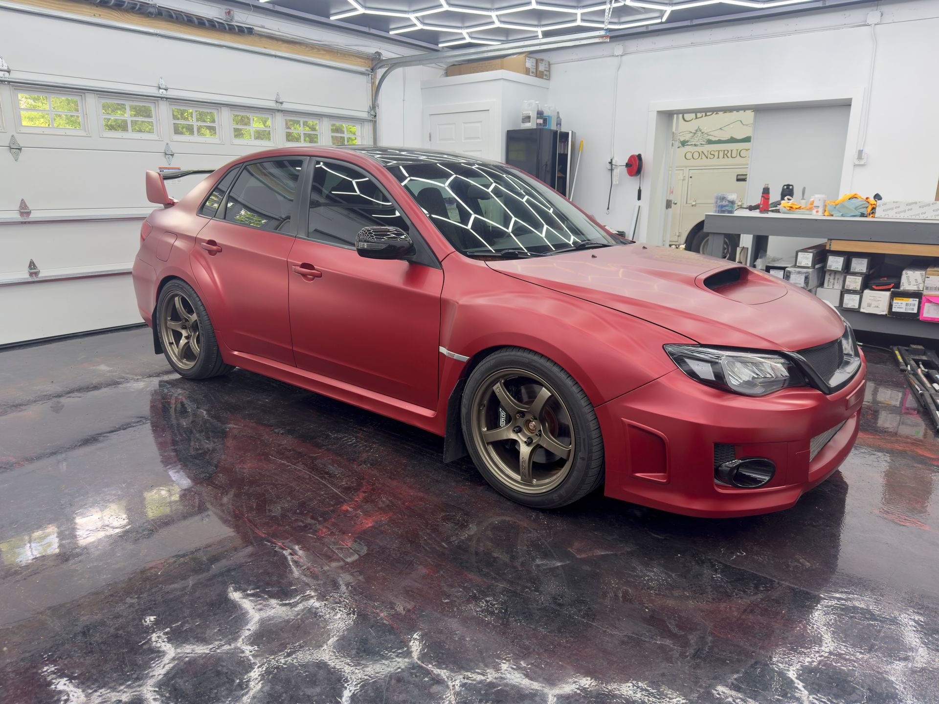 A red car is parked in a garage next to a garage door.