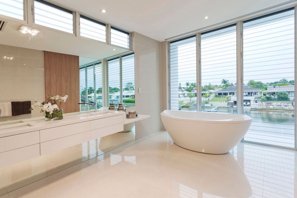 Moderno bagno bianco con vasca indipendente, ampie finestre con vista sul lungomare e mobile lavabo sospeso.