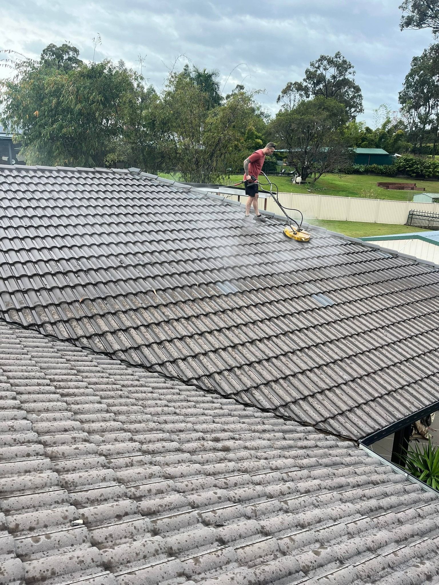 Person Washing a Tiled Roof With a Pressure Washer — Blast It Pressure Cleaning In Gold Coast, QLD