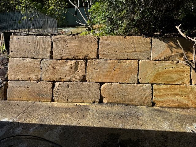 Sandstone Retaining Wall, Light Brown, With a Concrete Base, Set in a Garden With Trees and Foliage — Blast It Pressure Cleaning - Gold Coast In Gold Coast, QLD