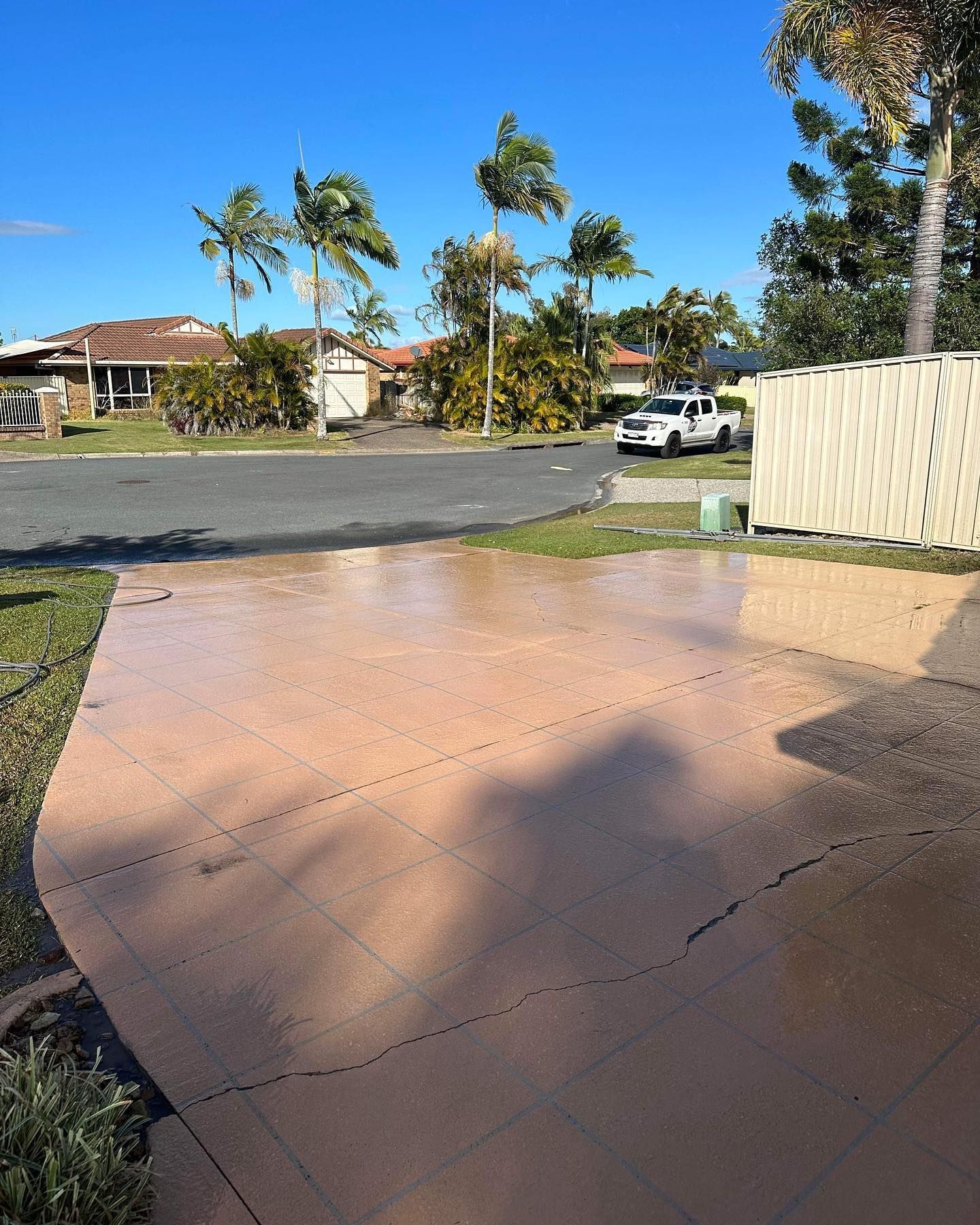 Wet Concrete Driveway in Residential Area With Palm Trees and a White Pickup Truck — Blast It Pressure Cleaning - Gold Coast In Gold Coast, QLD