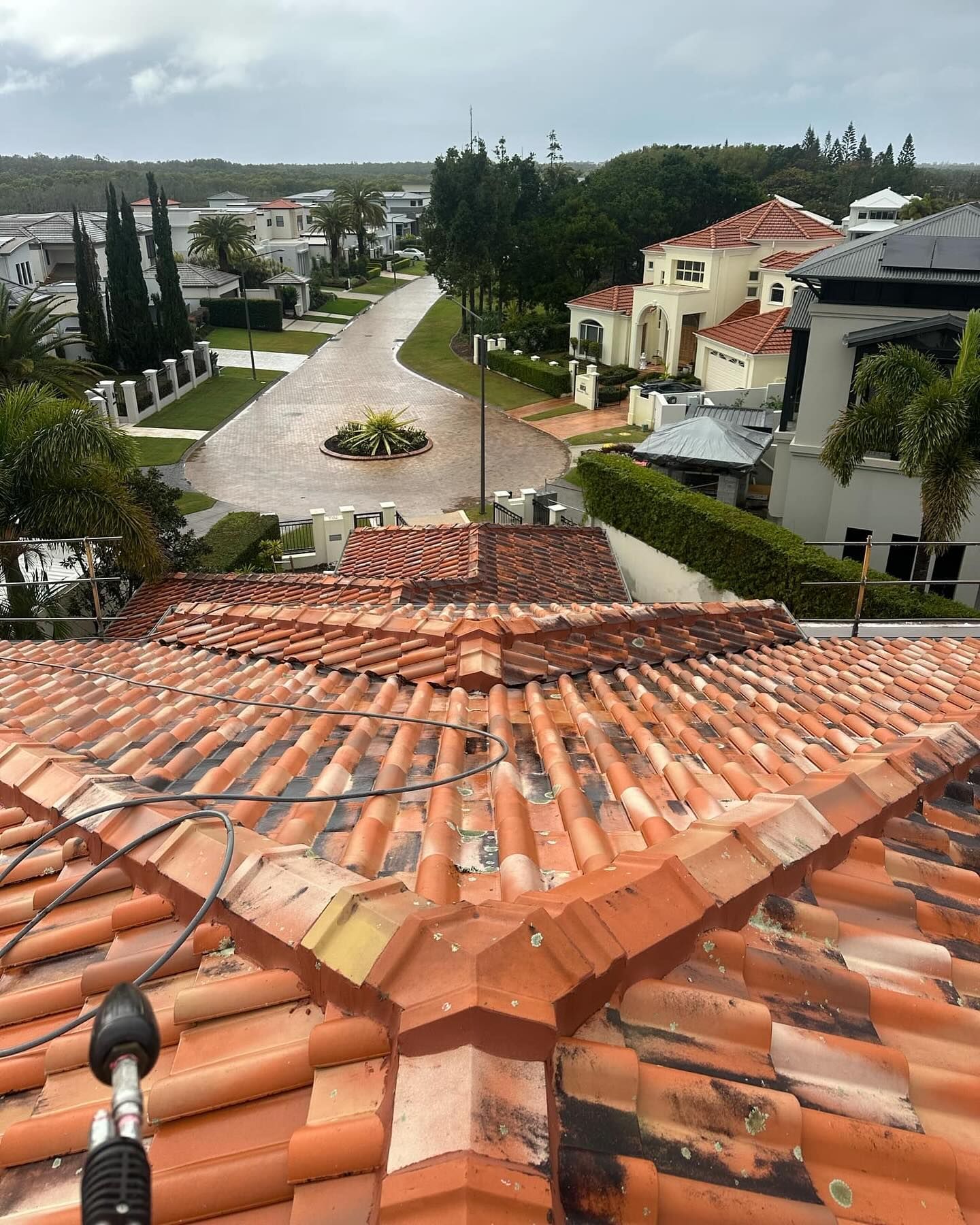 View from a terracotta tile roof overlooking a flooded street in a residential area.