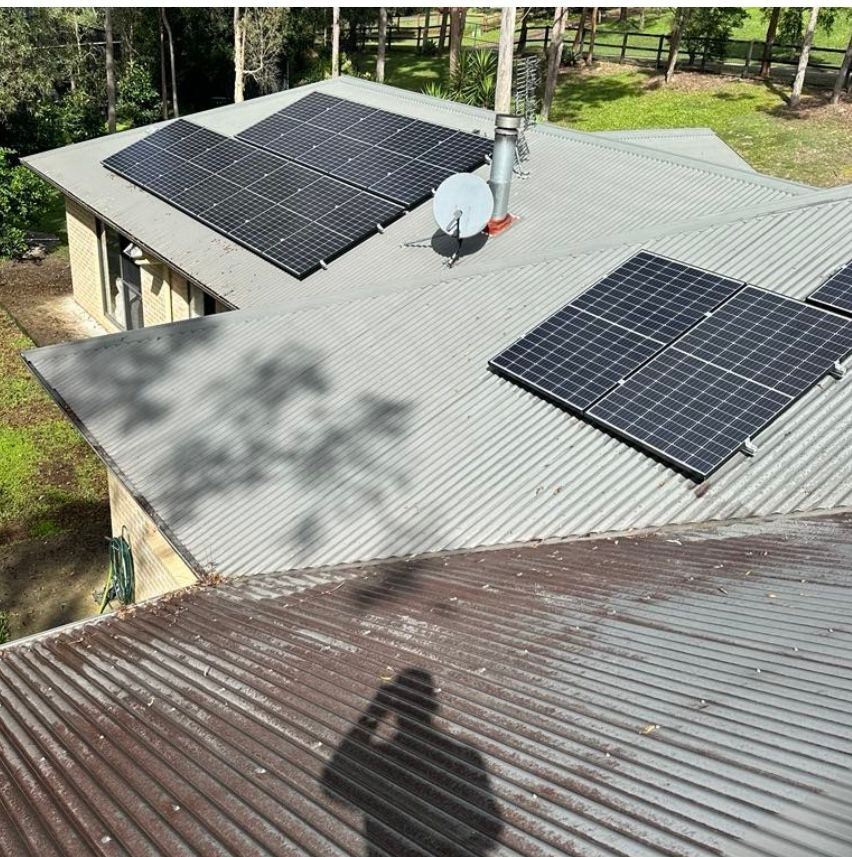 Person Cleaning Solar Panels on a White Roof — Blast It Pressure Cleaning - Gold Coast In Gold Coast, QLD
