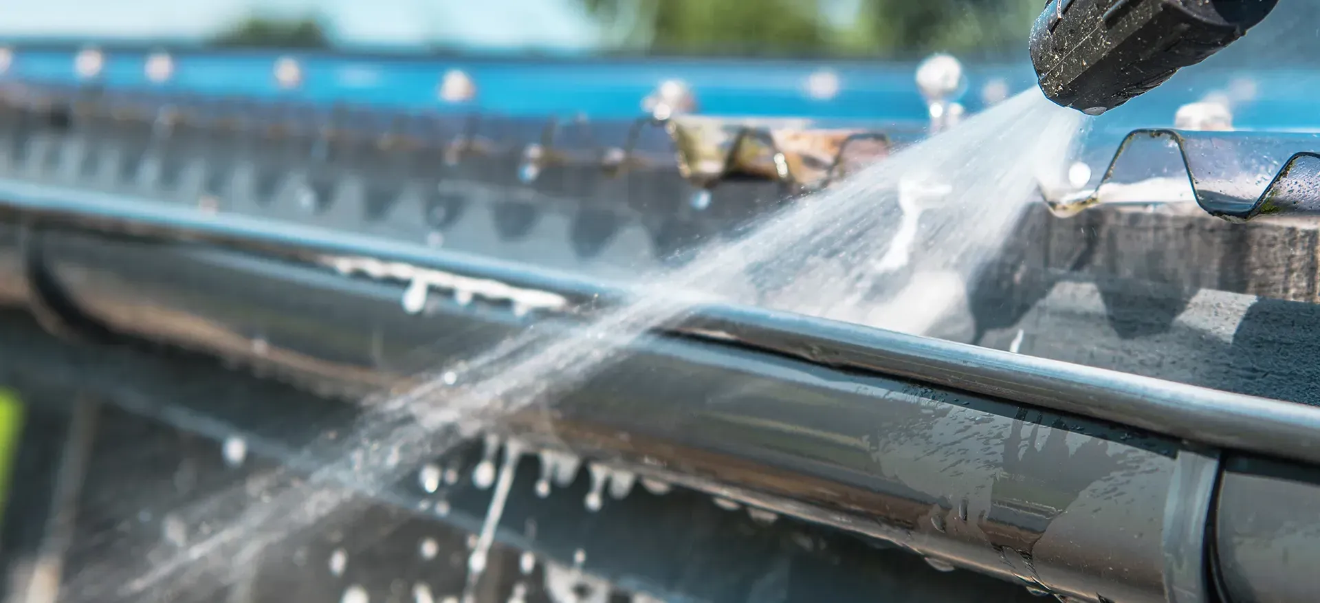 Gutter being cleaned with a pressure washer, spraying water — Blast It Pressure Cleaning - Gold Coast In Gold Coast, QLD