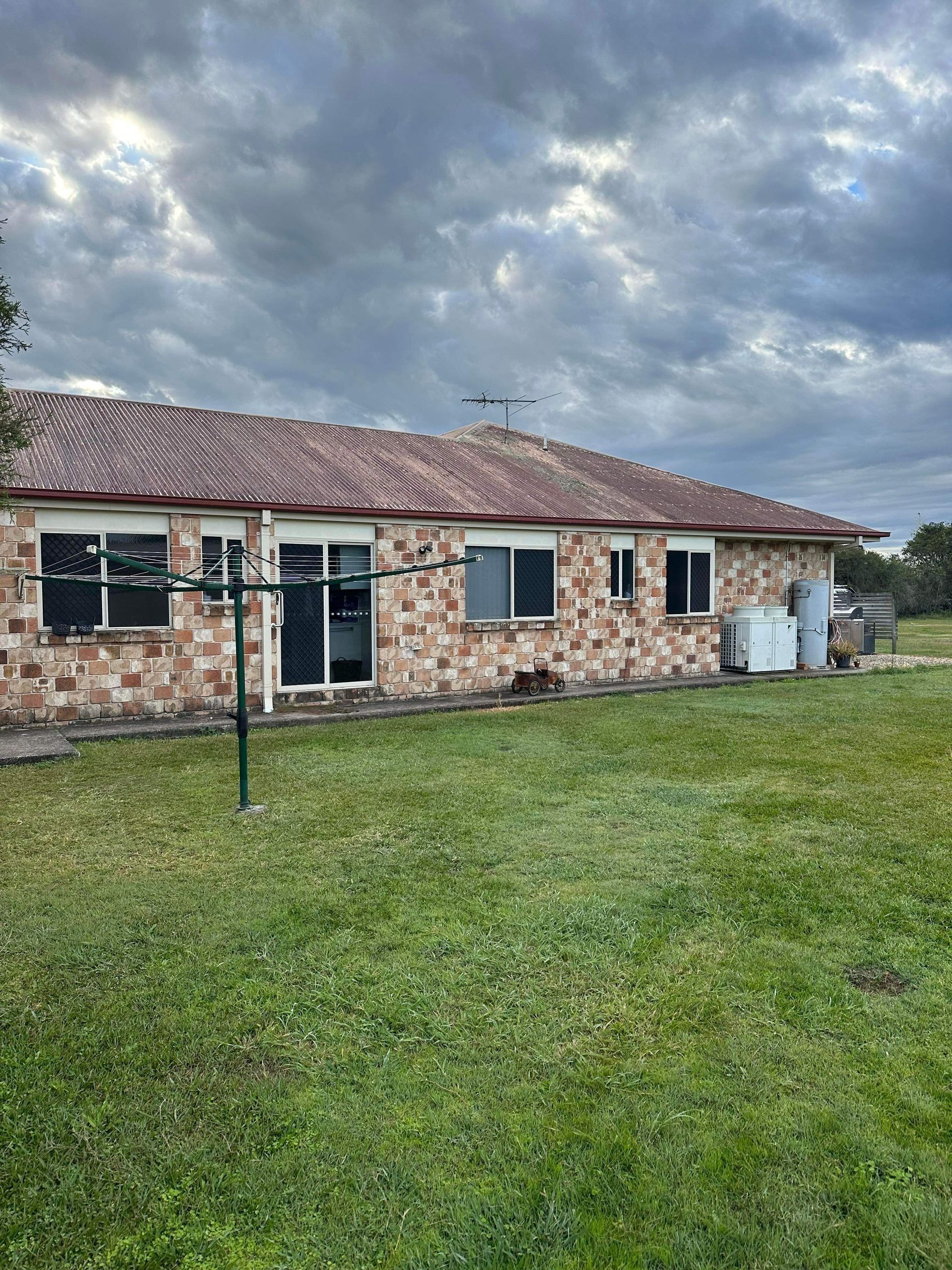 Back of brick house with a cloudy sky above the roof. Clothesline in the foreground.