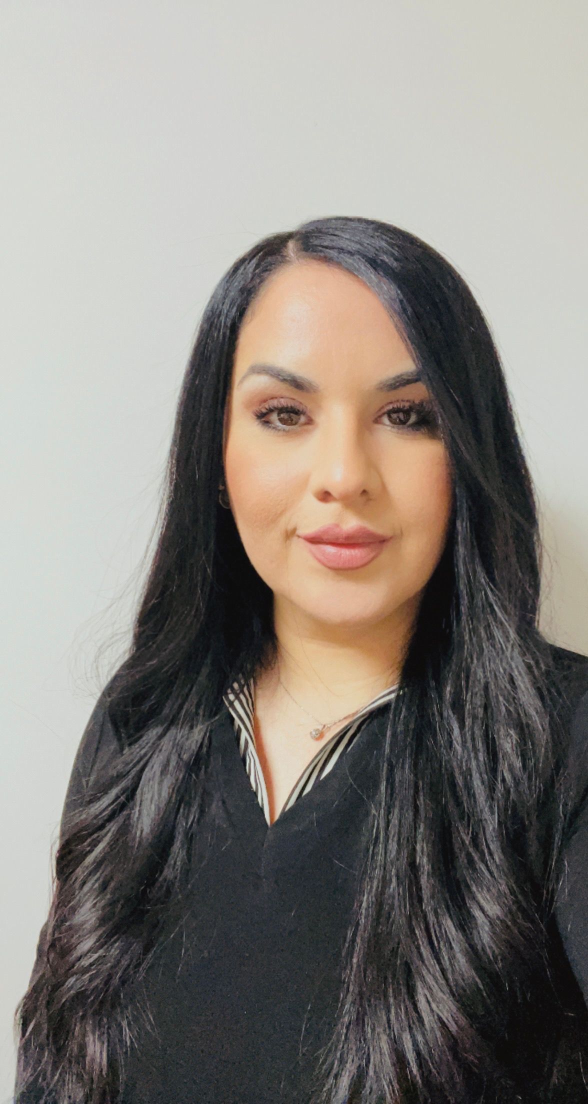 Woman in striped sweater and dark pants poses against a gray background.