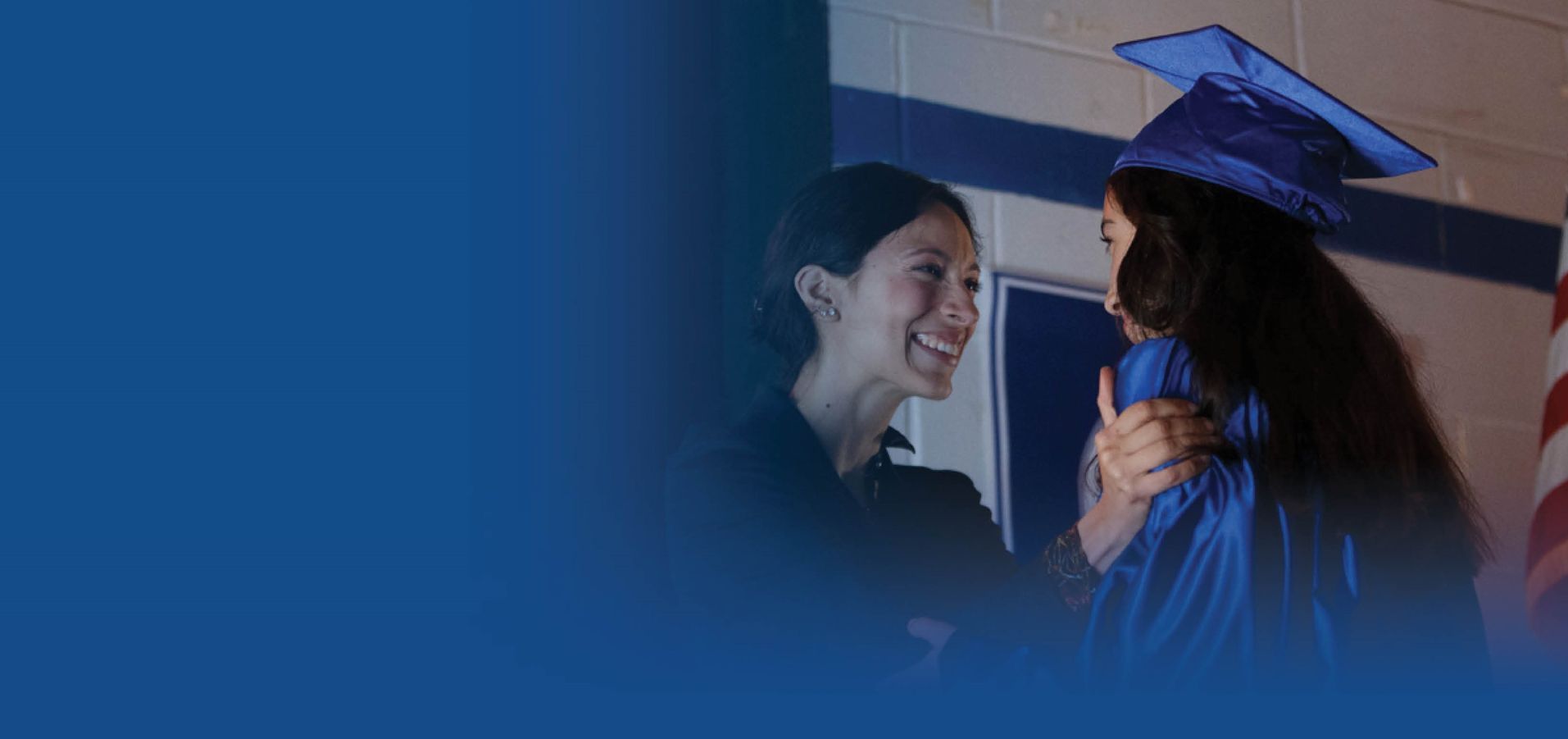 A woman is hugging a girl in a graduation cap and gown.