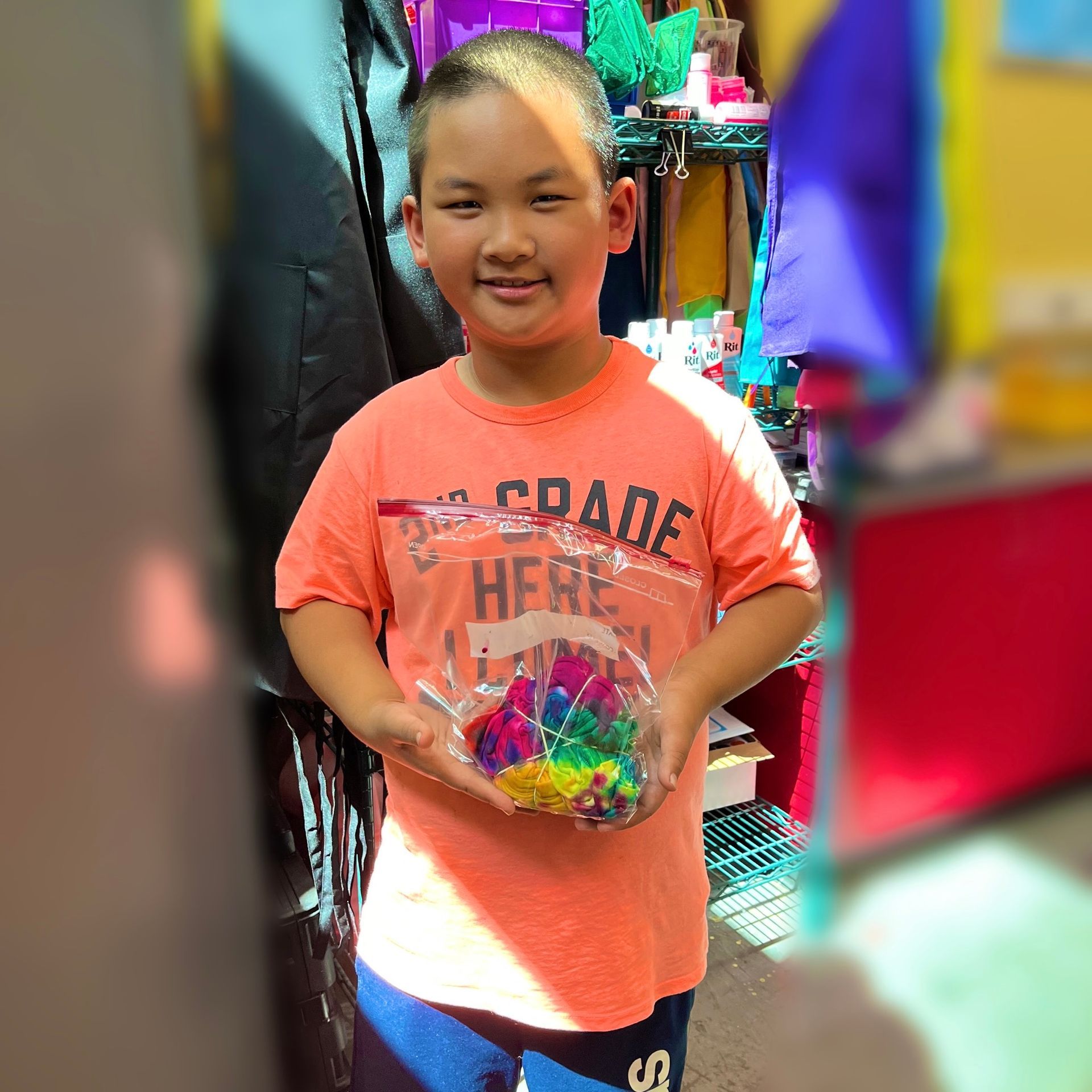 A young boy wearing an orange shirt that says grade here