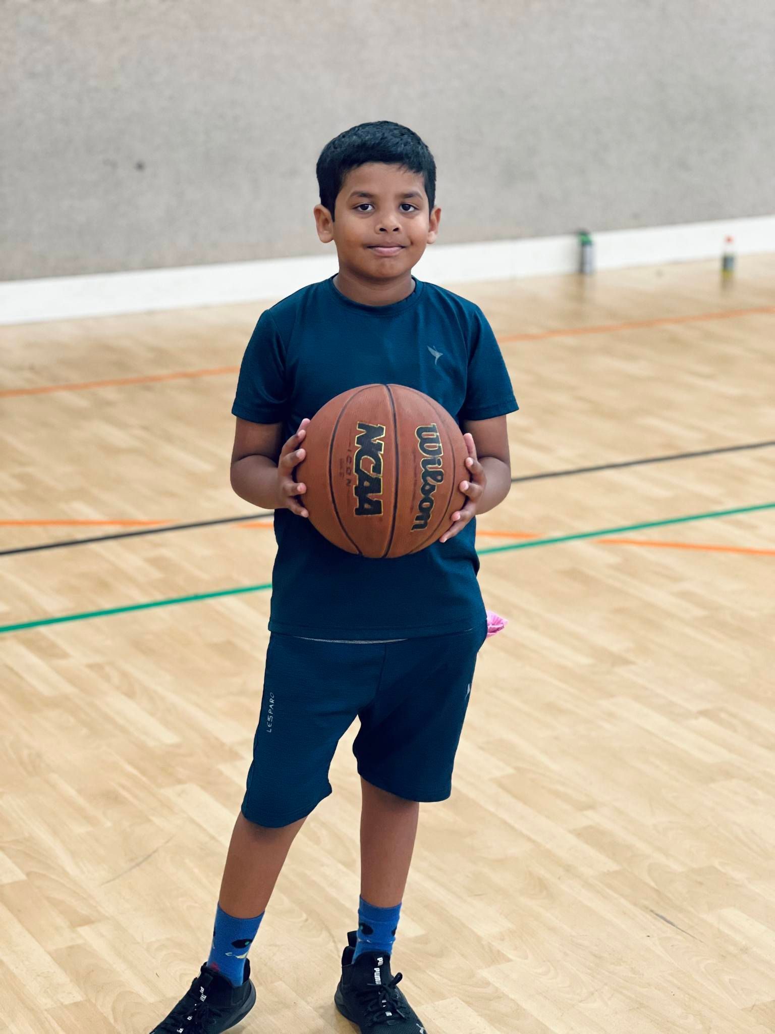 A young boy is holding a basketball on a court