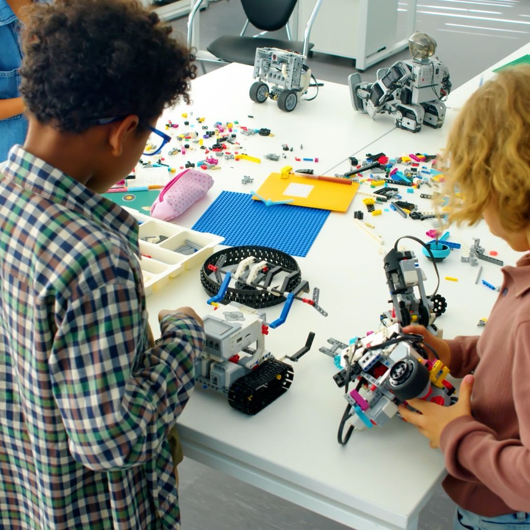 A group of children are playing with lego robots on a table