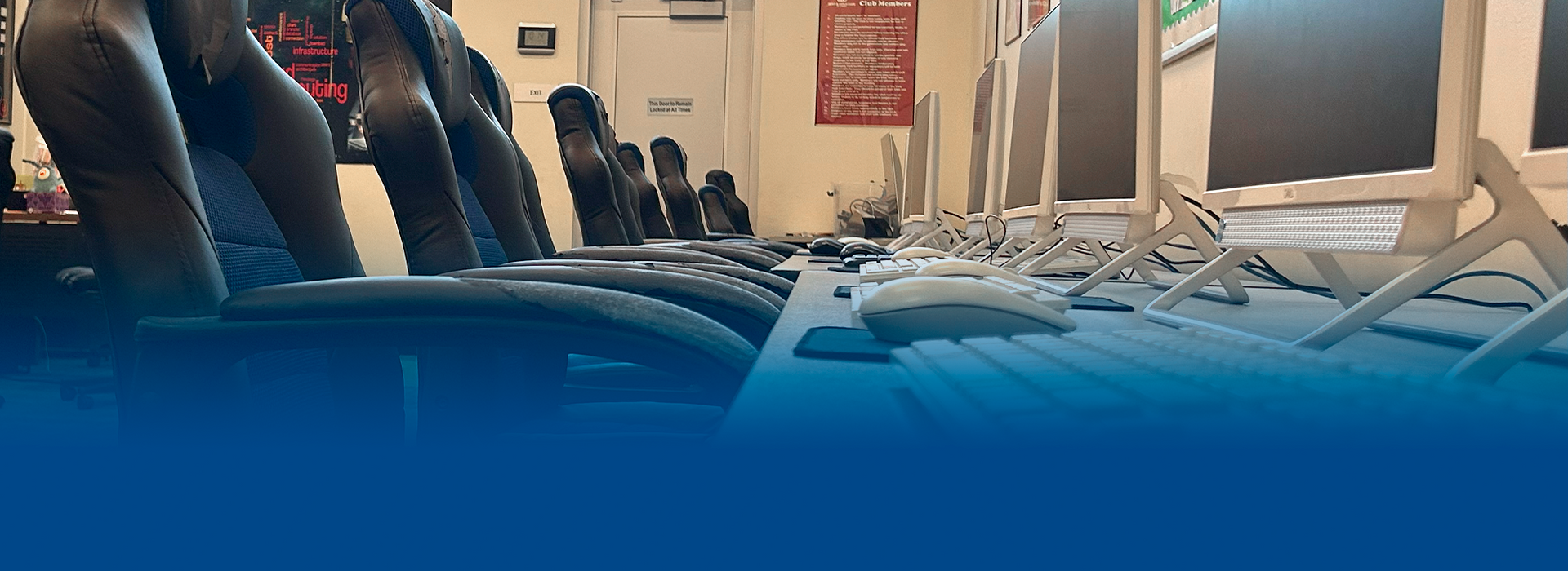 A row of chairs are sitting in front of a row of computer monitors.