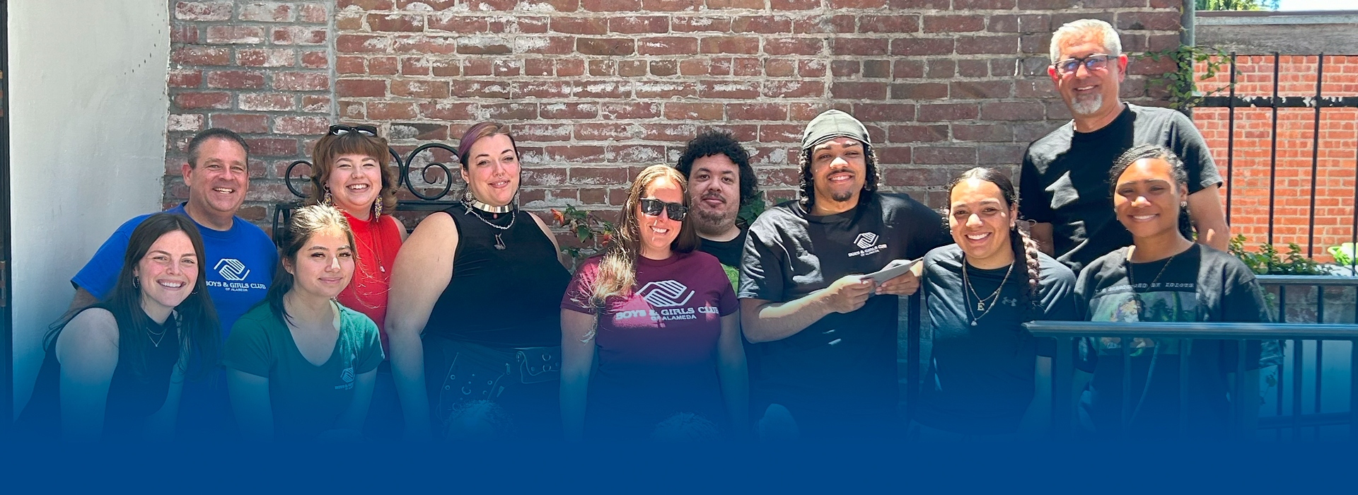 A group of people are posing for a picture in front of a brick wall.