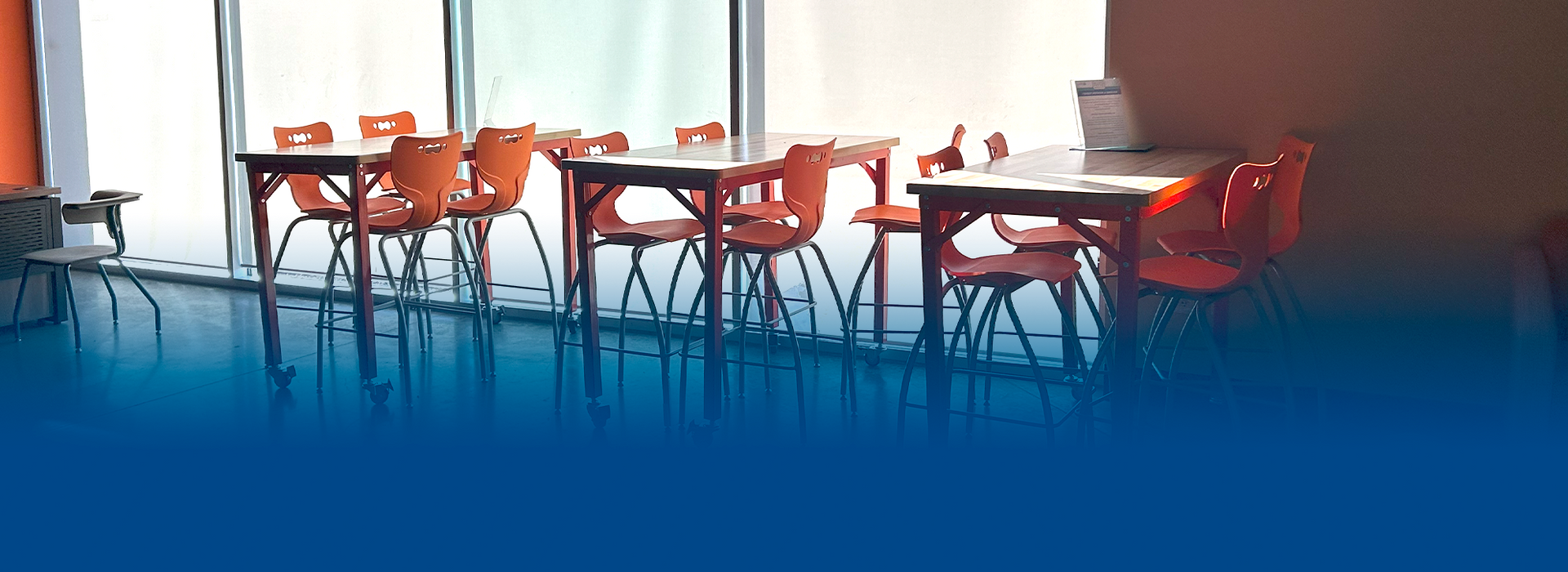 A row of tables and chairs in a room with a blue background.